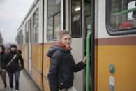 Cheerful young woman in warm outerwear before getting in public transport