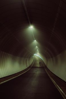 A solitary figure walks through a dimly lit tunnel, creating a mysterious and serene atmosphere.