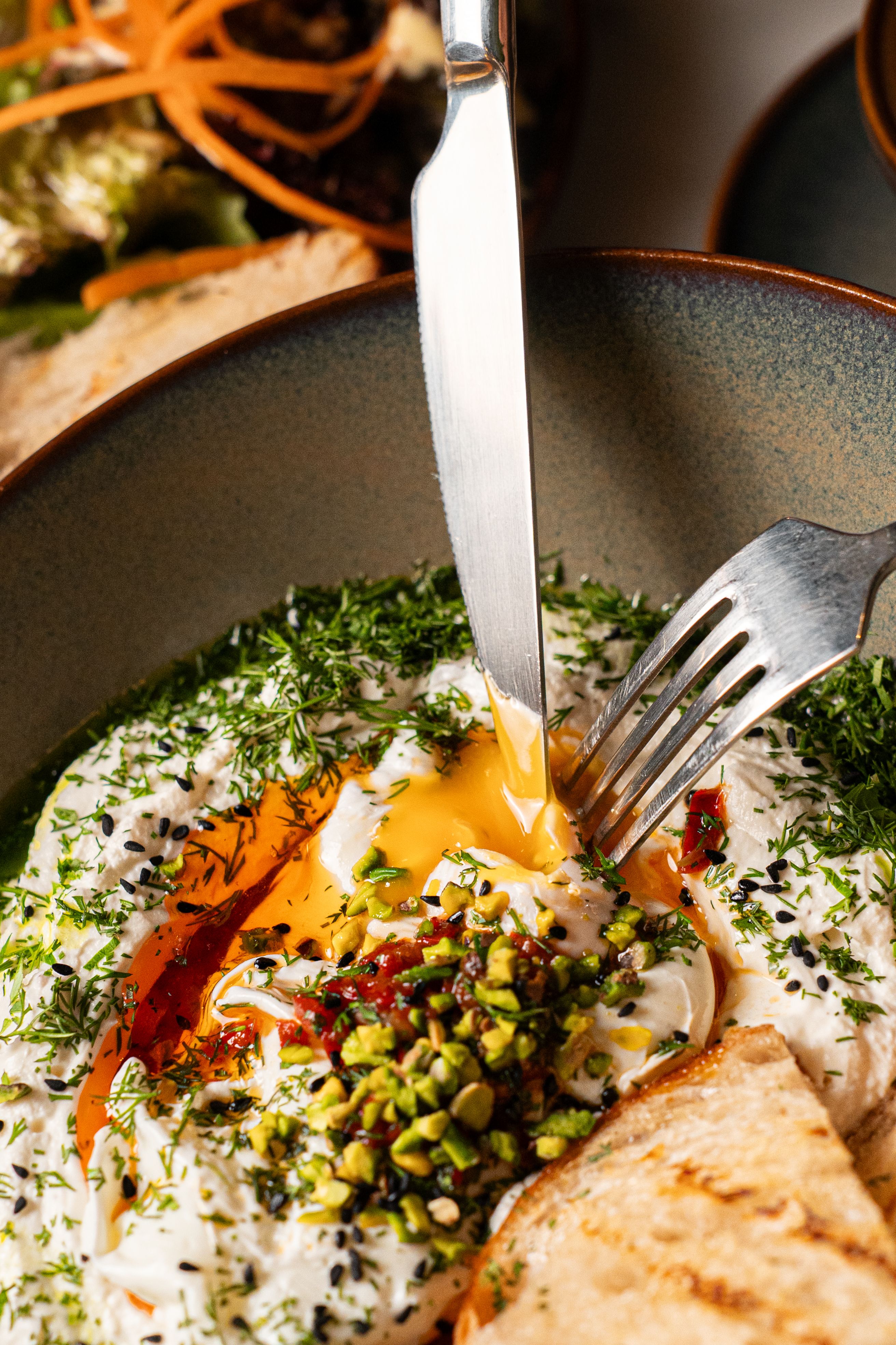 Creamy labneh topped with herbs, pistachios, and olive oil, served with grilled bread.
