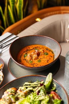 Gourmet tomato soup garnished with herbs and spices in a fine dining setting.