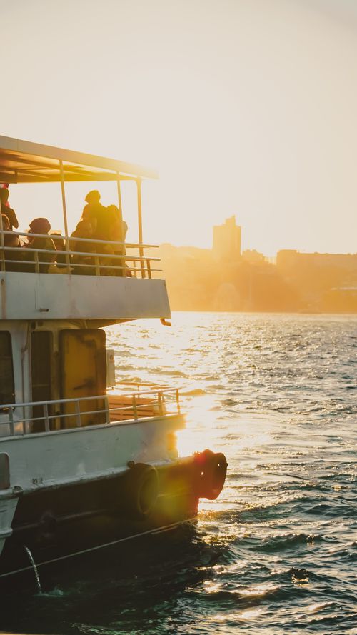 Free A boat navigates tranquil waters at sunset with passengers enjoying the scenic view. Stock Photo
