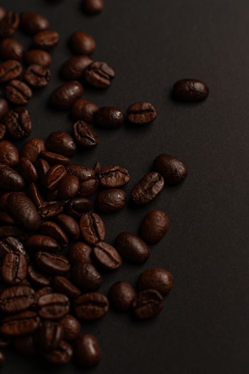 Free Richly roasted coffee beans on a dark surface, showcasing texture and color. Stock Photo
