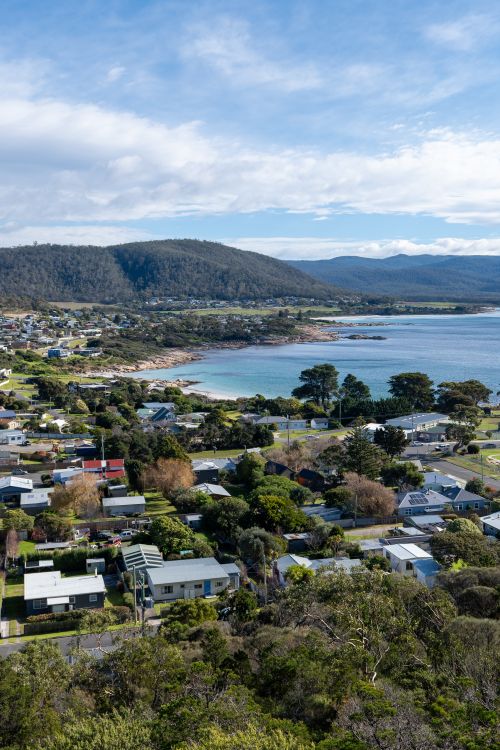Free Aerial view of a picturesque coastal town with houses, greenery, and coastline. Stock Photo