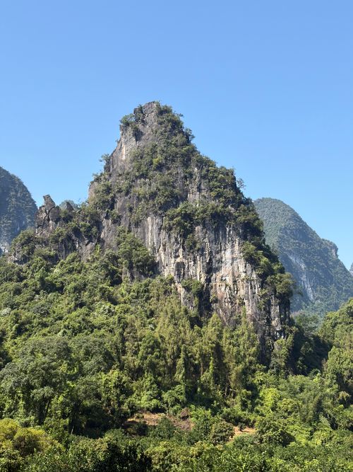 Free Breathtaking view of a karst mountain surrounded by lush greenery under a clear sky in Yangshuo, China. Stock Photo