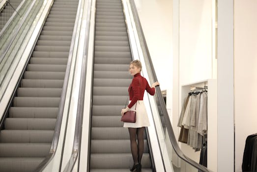 Elegant woman going up an escalator in a stylish indoor shopping mall.