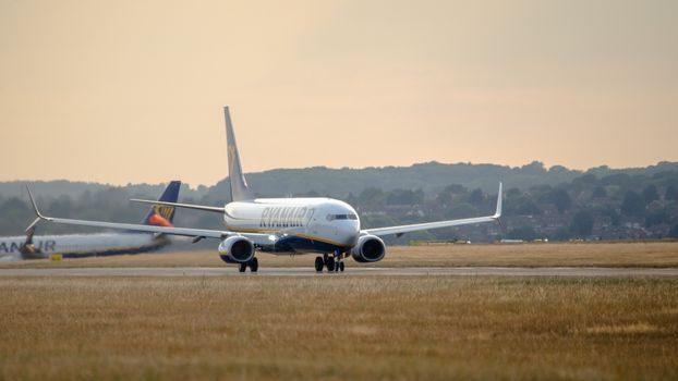 A Ryanair Boeing 737 taxiing on runway during golden hour at Luton Airport.
