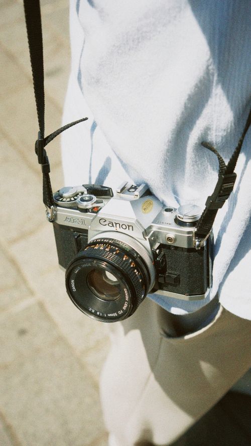 Free Close-up of a vintage camera hanging on a person's neck strap outdoors, capturing nostalgic vibes. Stock Photo