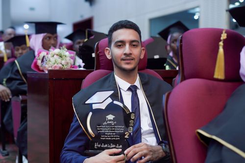 Free A proud graduate holding a trophy during a graduation ceremony, seated among peers. Stock Photo