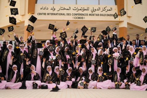 Free Group of graduates celebrating outside a conference center with caps thrown in the air. Stock Photo