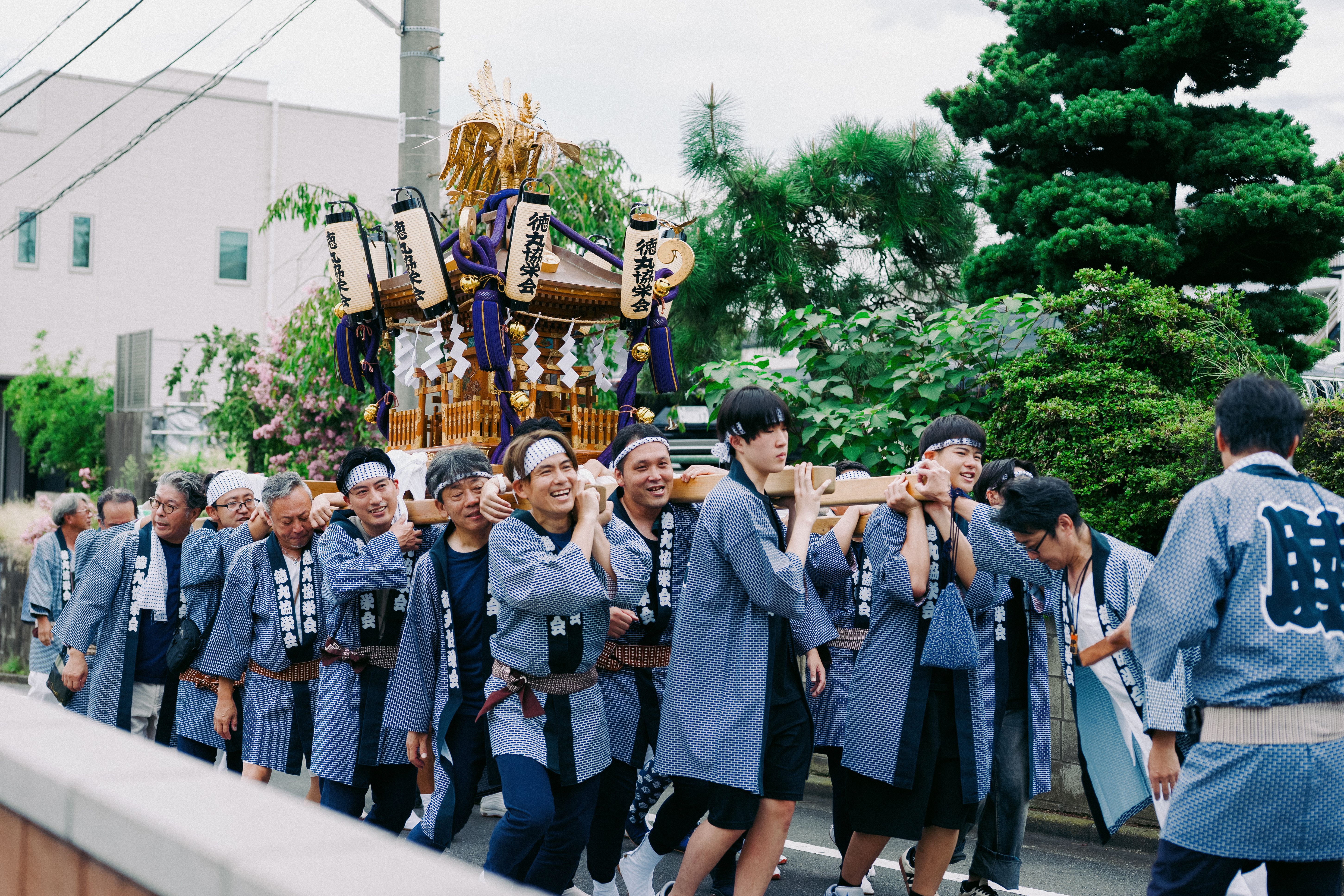 男性たちが神輿を担いで行進する、活気あふれる祭りの行列。文化的な伝統が披露される。