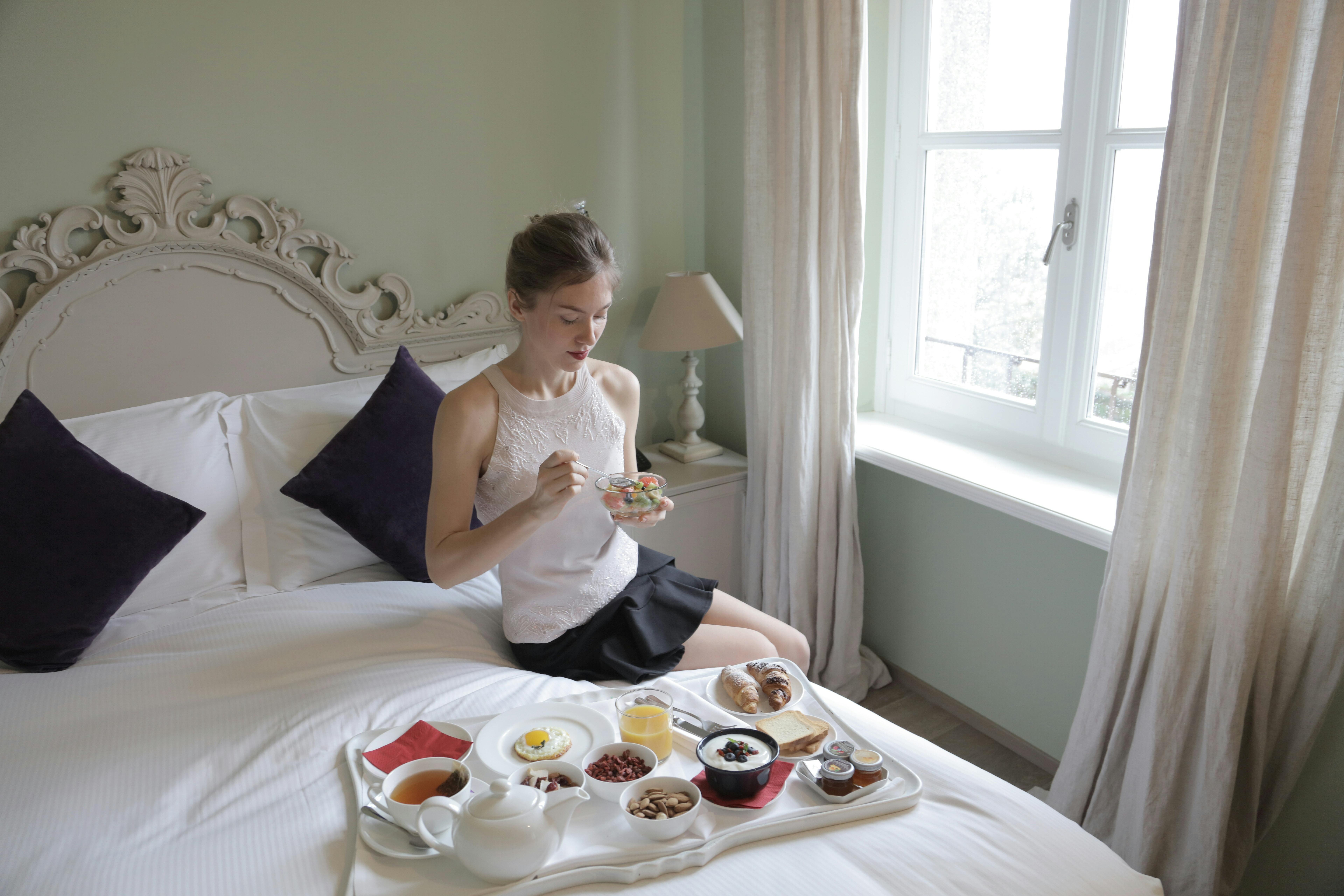 Young attractive woman having breakfast on bed · Free Stock Photo