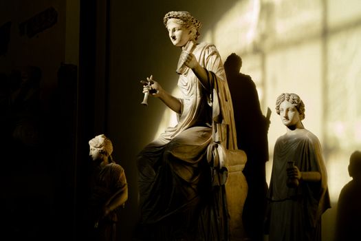 Ancient Roman sculptures in the Vatican Museum under dramatic lighting and shadows.