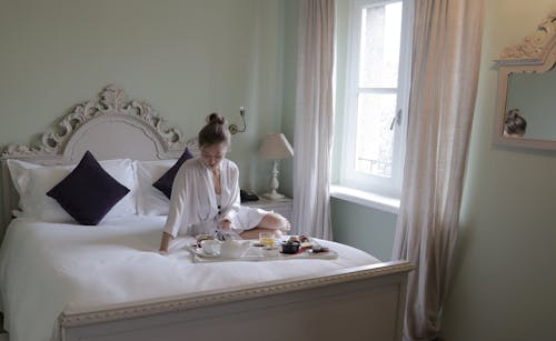 Woman In White Robe Sitting On Bed