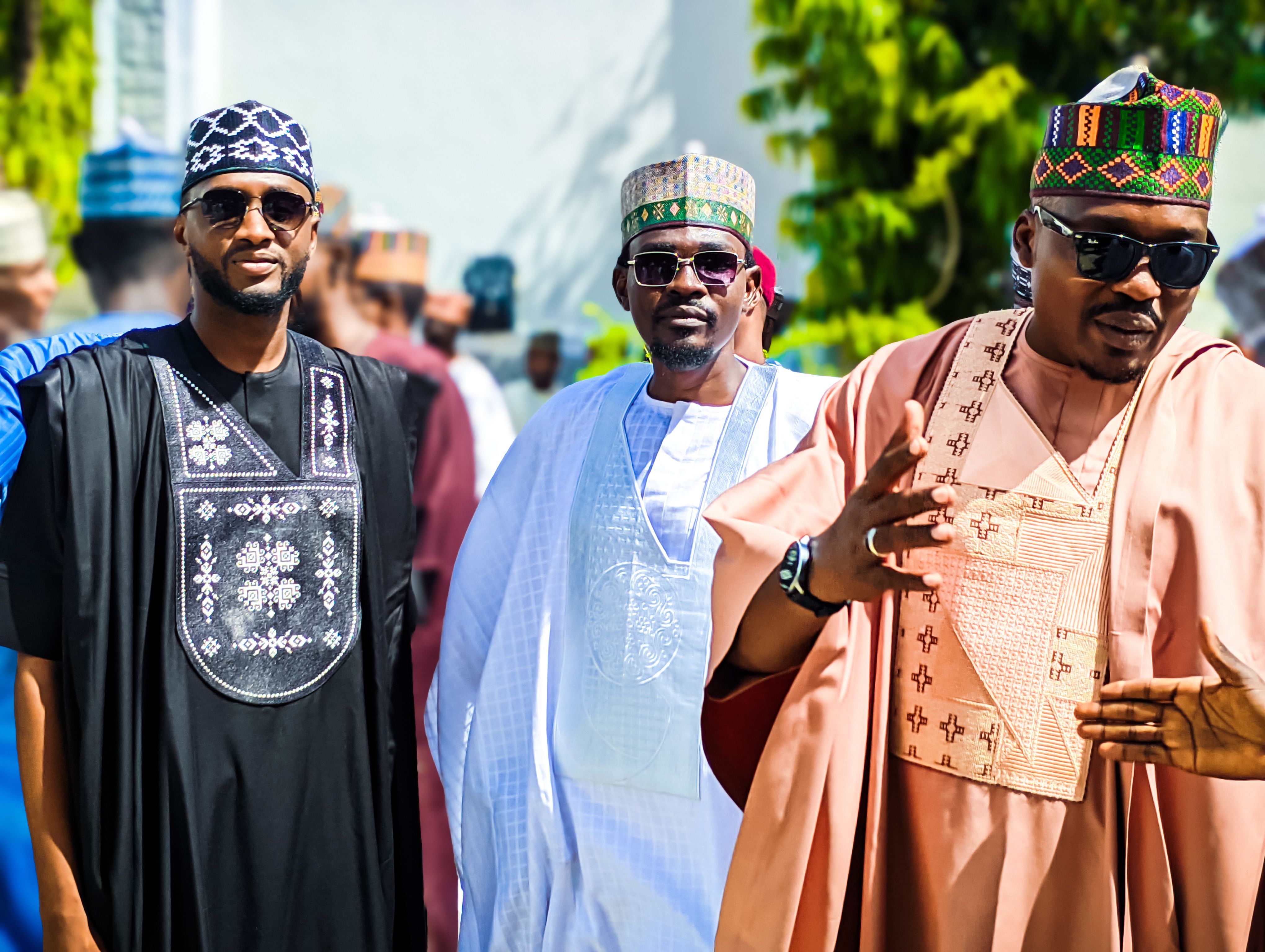 Men dressed in vibrant traditional African clothing outdoors at a cultural event.