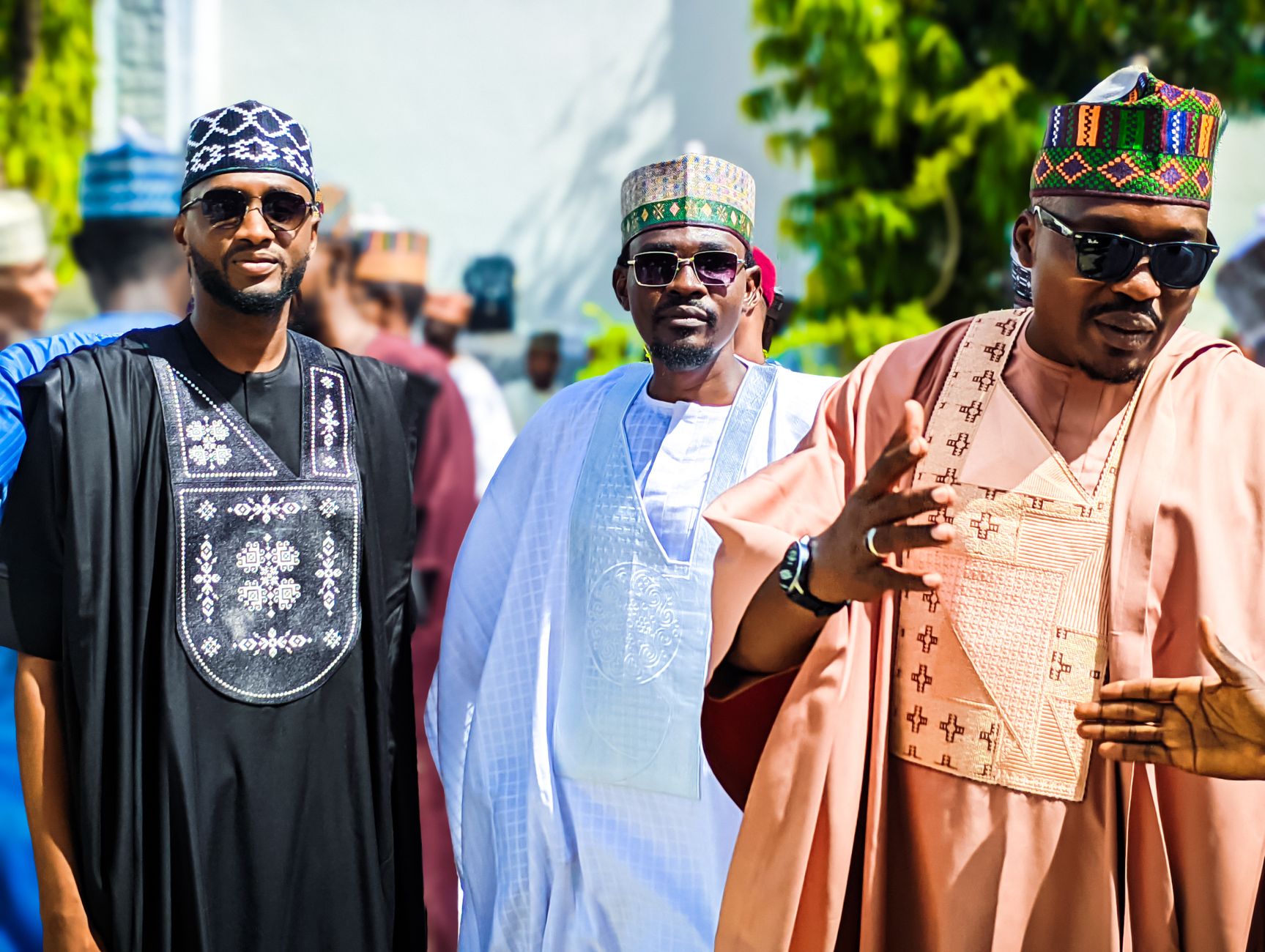 Men dressed in vibrant traditional African clothing outdoors at a cultural event.