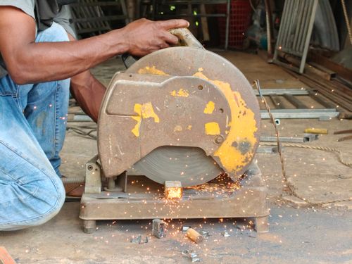 Free A worker uses a circular saw to cut metal, generating sparks in a workshop. Stock Photo