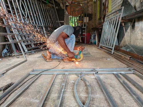 Free Metalworker using an angle grinder cutting steel, producing a stream of sparks in an industrial workshop. Stock Photo