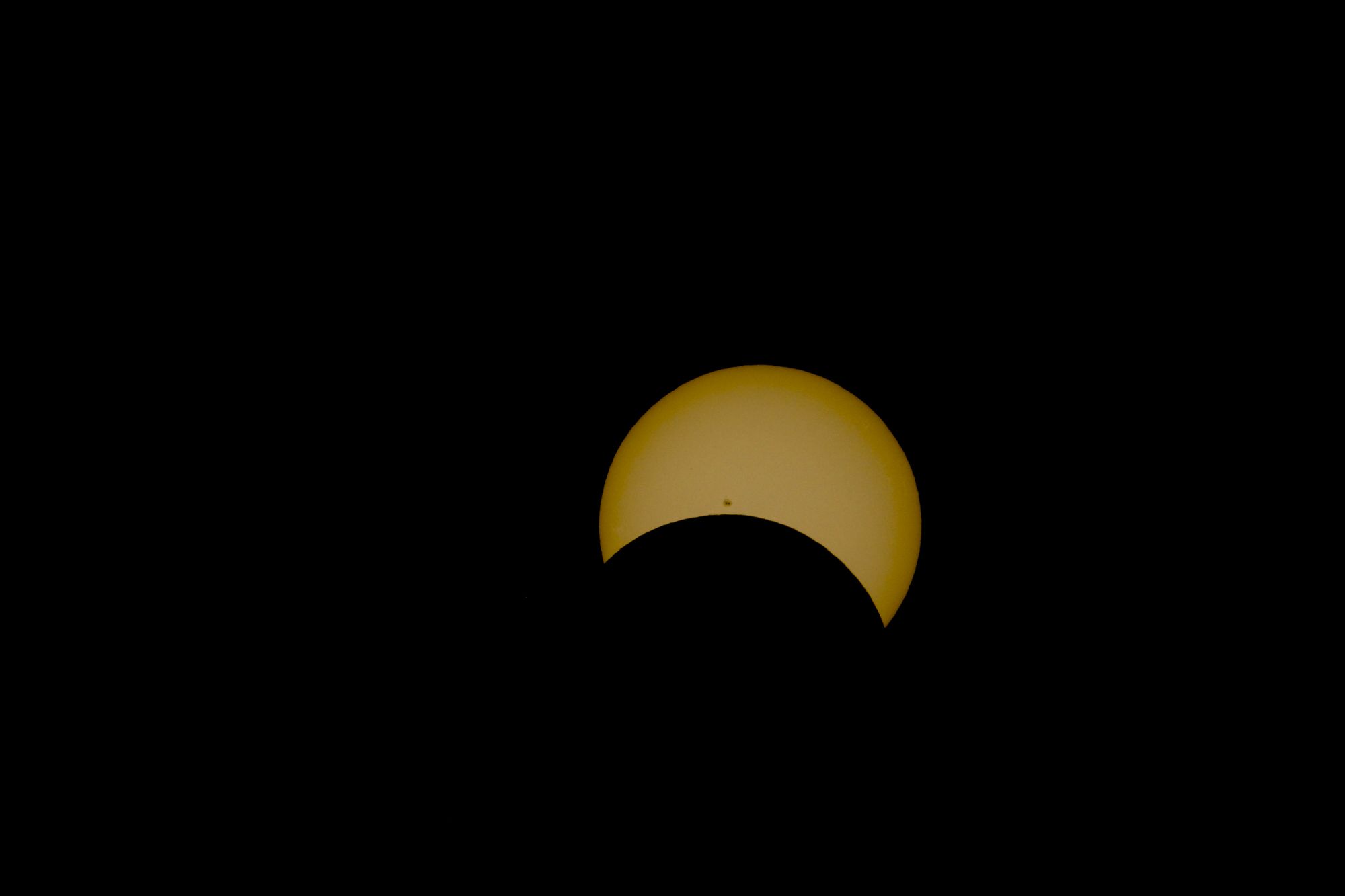 Dramatic partial solar eclipse showcasing a distinct sun spot against a dark sky.