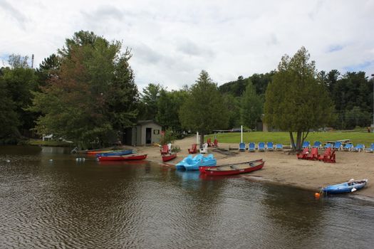 Lakeside beach in Huntsville, Ontario with canoes and trees, perfect for a summer day.
