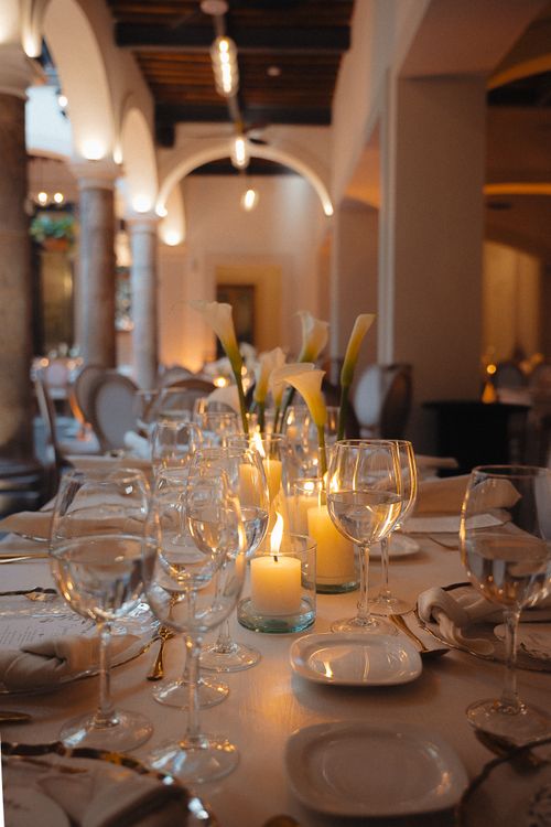 Free A beautifully arranged candlelit dinner table setting in an elegant indoor venue with classic architecture. Stock Photo
