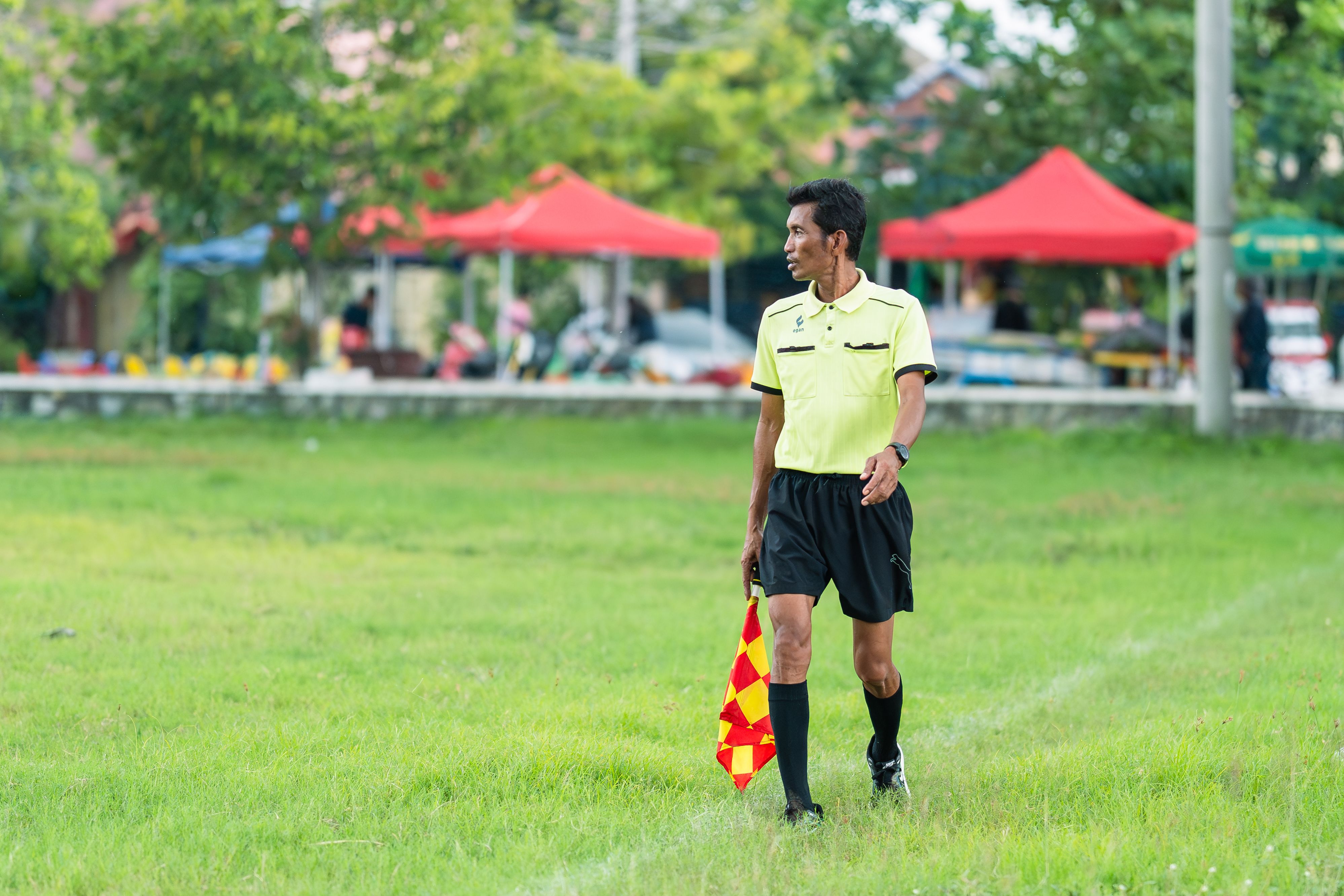 An assistant referee holding a flag on a football field during a match.