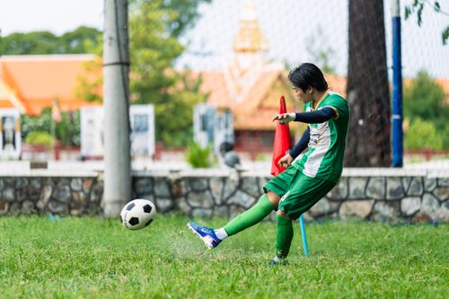 Free Dynamic shot of a young soccer player kicking a football on an outdoor field during the day. Stock Photo