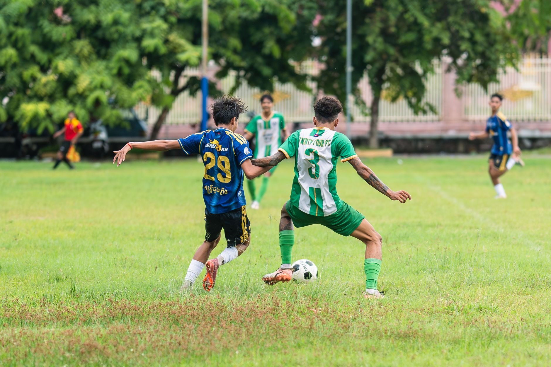 Soccer players in action on a lush green field during a daytime match.