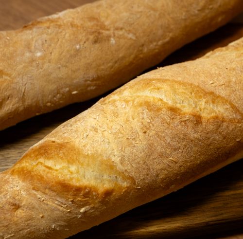 Free Two freshly baked baguettes on a wooden surface, showcasing their golden crust and texture. Stock Photo