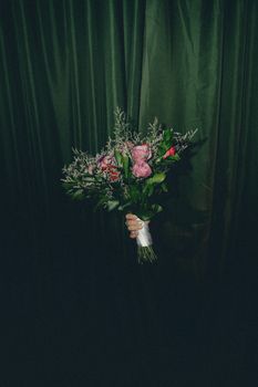 A vibrant pink bouquet held against a dark green curtain backdrop. Perfect for floral decor inspiration.