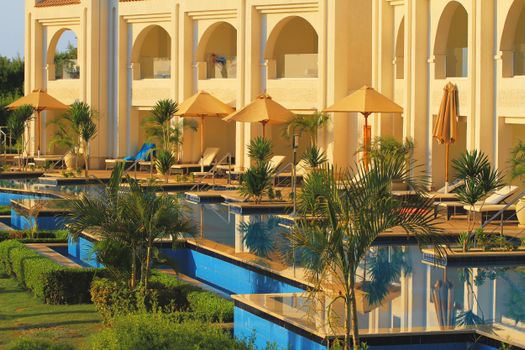 Elegant hotel poolside with sun loungers and umbrellas, perfect for a summer retreat.