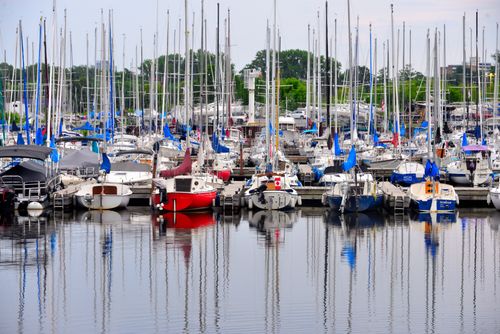 Free A vibrant marina filled with colorful sailboats and yachts reflected on calm water, perfect for summer travel imagery. Stock Photo