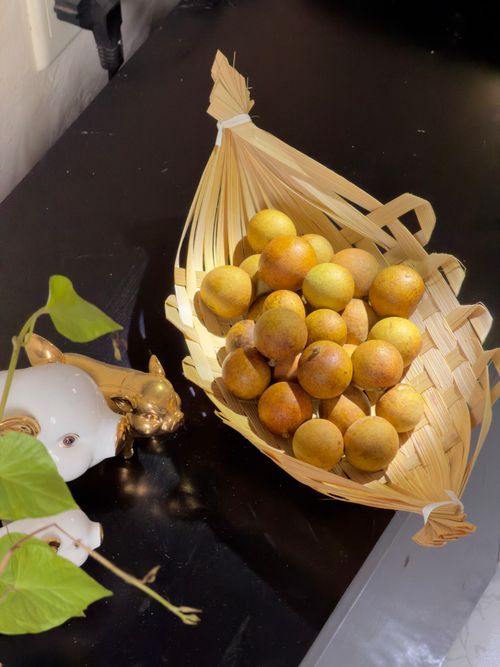 Free A basket of fresh longan fruit on a dark table with natural light indoors. Stock Photo