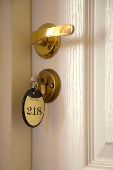 Close-up of a hotel room key tagged '218' on a stylish door handle, symbolizing hospitality.