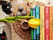 Various flowers and books placed on table with chocolates near vintage typewriter