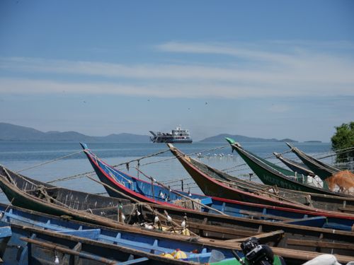 Free Colorful fishing boats on the shore in Mbita, Kenya with a ferry in the distance. Stock Photo