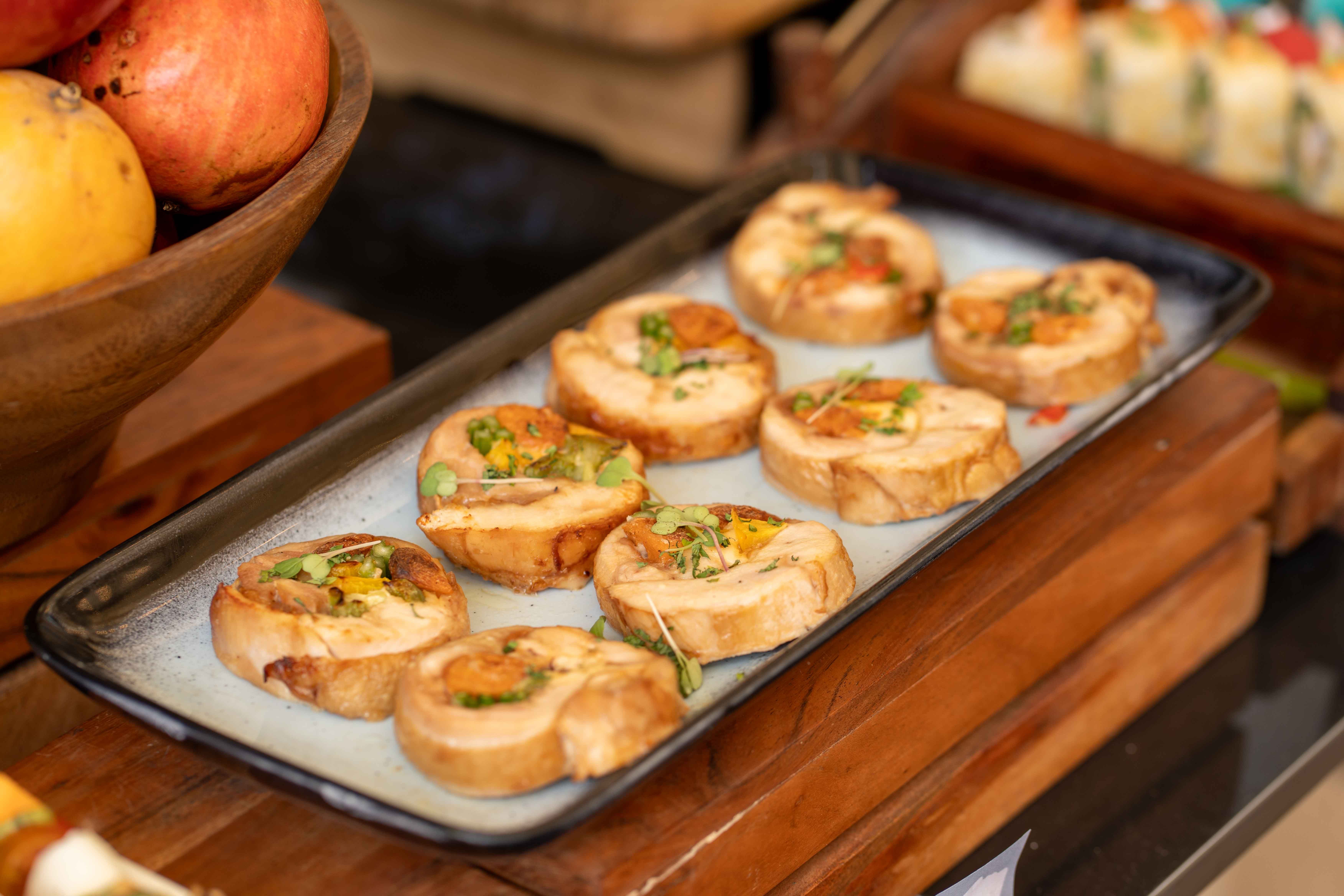 Gourmet chicken roulade served on a dark ceramic platter, garnished with fresh herbs.