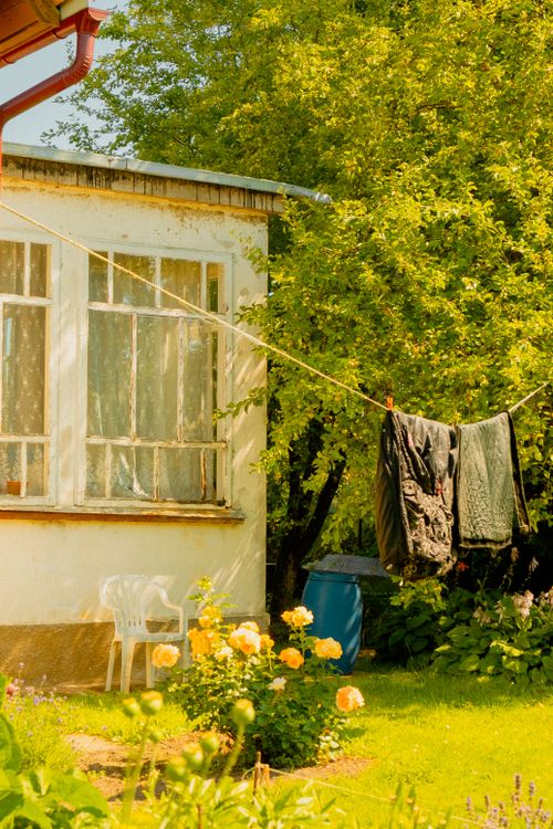 Free A sunny garden scene featuring clothes drying on a line beside a flower bed and vintage house. Stock Photo