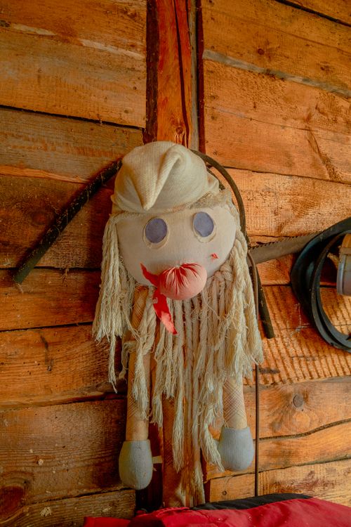 Free Unique handmade doll hanging on a rustic wooden wall, creating an artistic and vintage atmosphere. Stock Photo