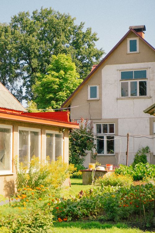 Free Rustic house with a vibrant garden on a sunny day, showcasing rural charm. Stock Photo