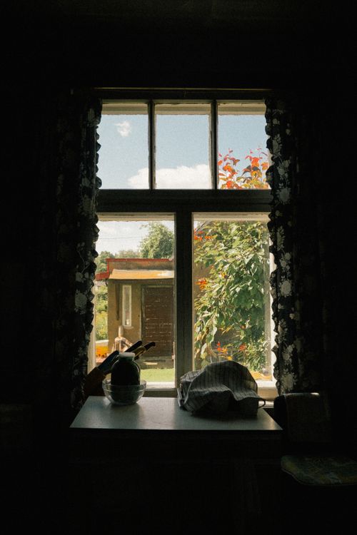 Free Warm view through a kitchen window revealing a lush garden under a bright sky. Stock Photo