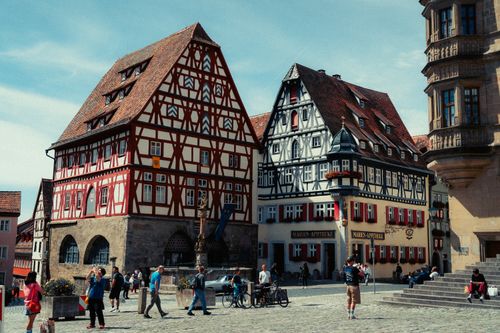 Free Traditional half-timbered buildings in Rothenburg ob der Tauber, Germany, with tourists exploring the picturesque streets. Stock Photo