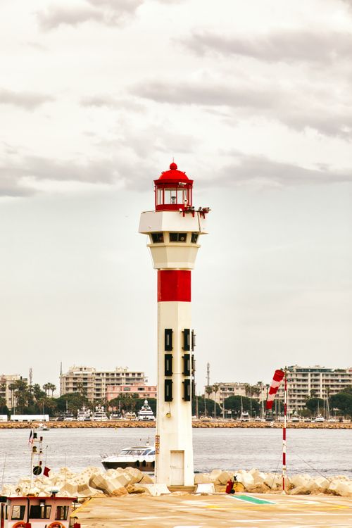 Free Picturesque lighthouse stands tall in Cannes harbor, offering a serene coastal view. Stock Photo