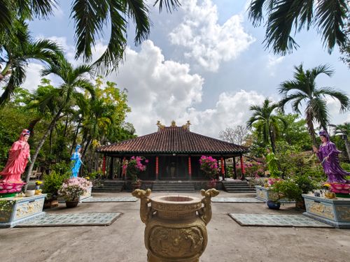 Free A tranquil courtyard in a Vietnamese pagoda with vibrant statues and lush palms in Ho Chi Minh City. Stock Photo
