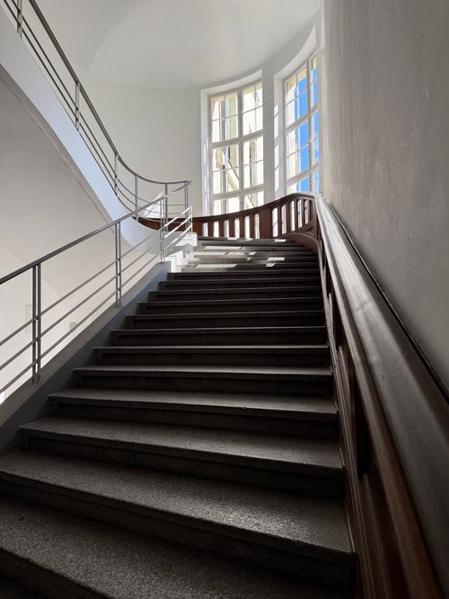 Free A beautifully lit staircase with metal railings and big windows in a historic Munich building. Stock Photo