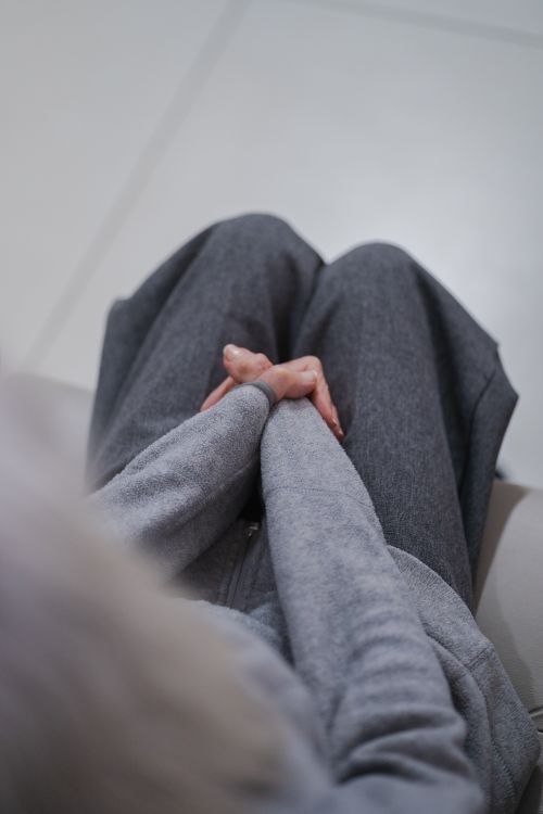 Free A serene top-down view of a senior adult in a cozy gray outfit with hands clasped, exuding calm. Stock Photo