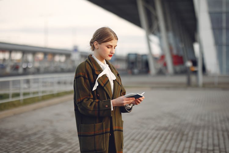 Young Confident Woman Reading Documents While Standing Near Airport Terminal