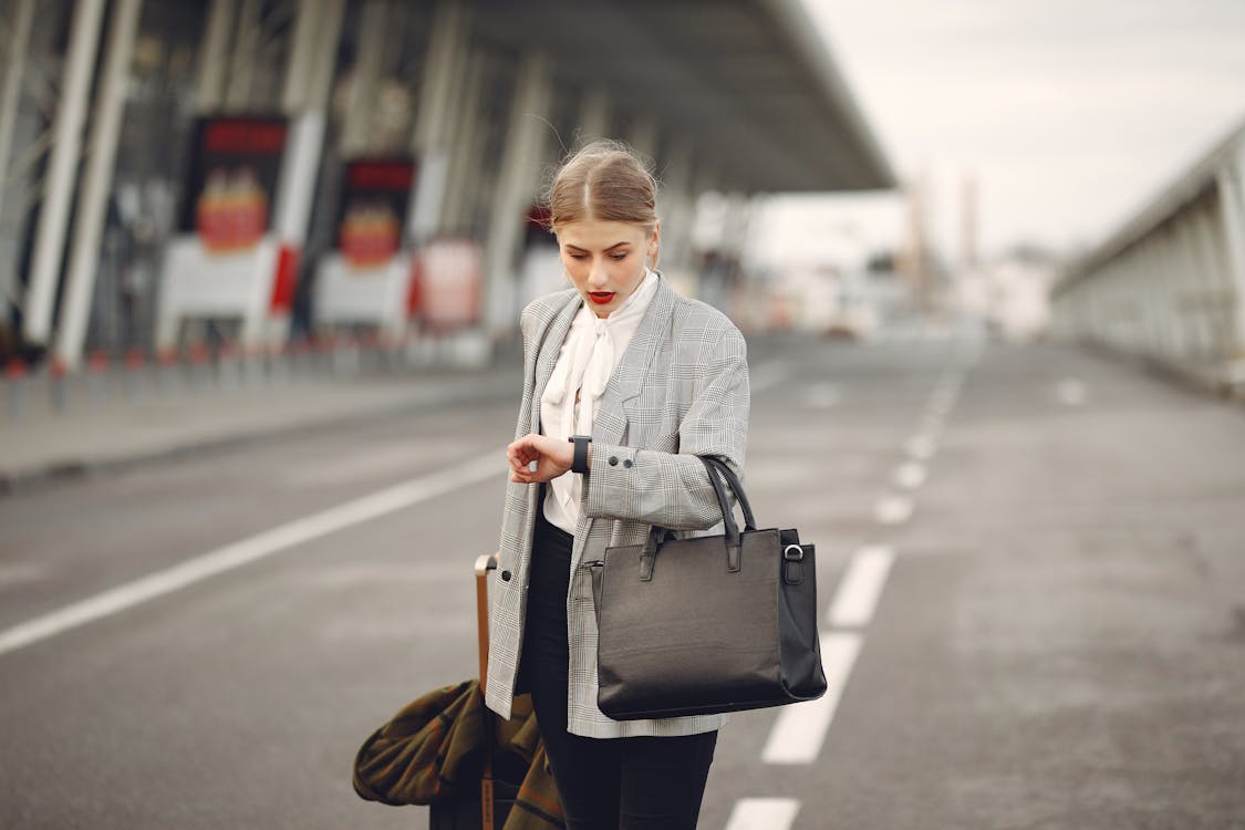 Free Worried young businesswoman with suitcase hurrying on flight on urban background Stock Photo