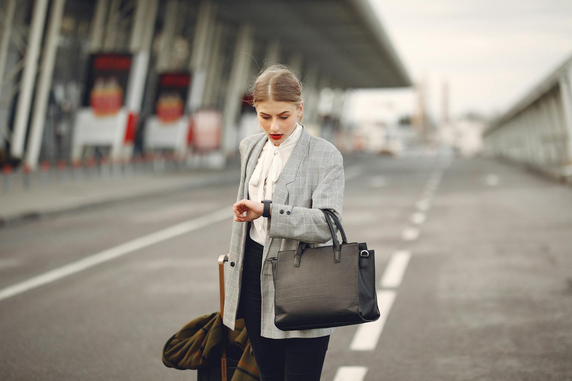 Worried young businesswoman with suitcase hurrying on flight on urban background
