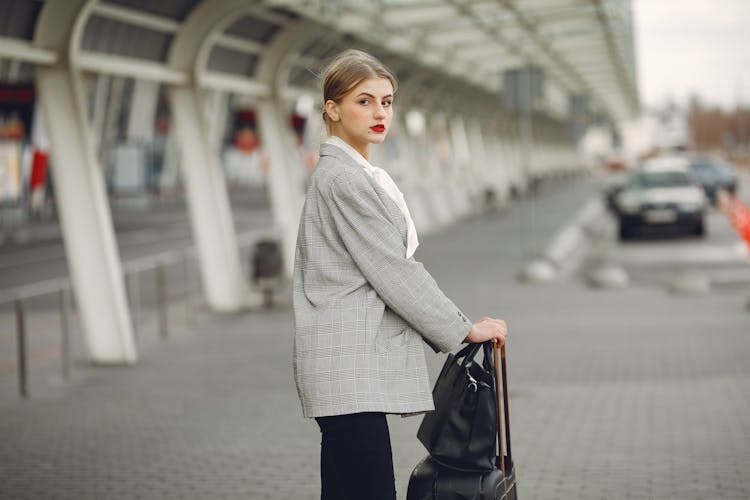 Stylish Young Woman With Suitcase Near Car Parking In Airport