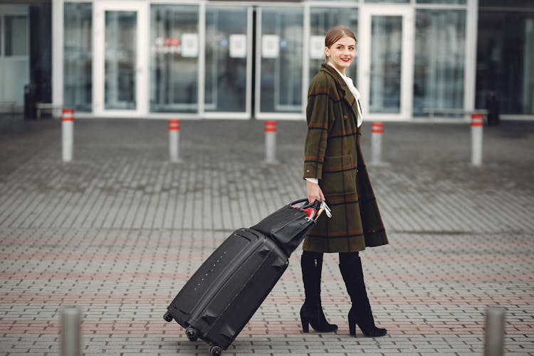 Stylish Young Woman Walking With Luggage Near Airport Terminal